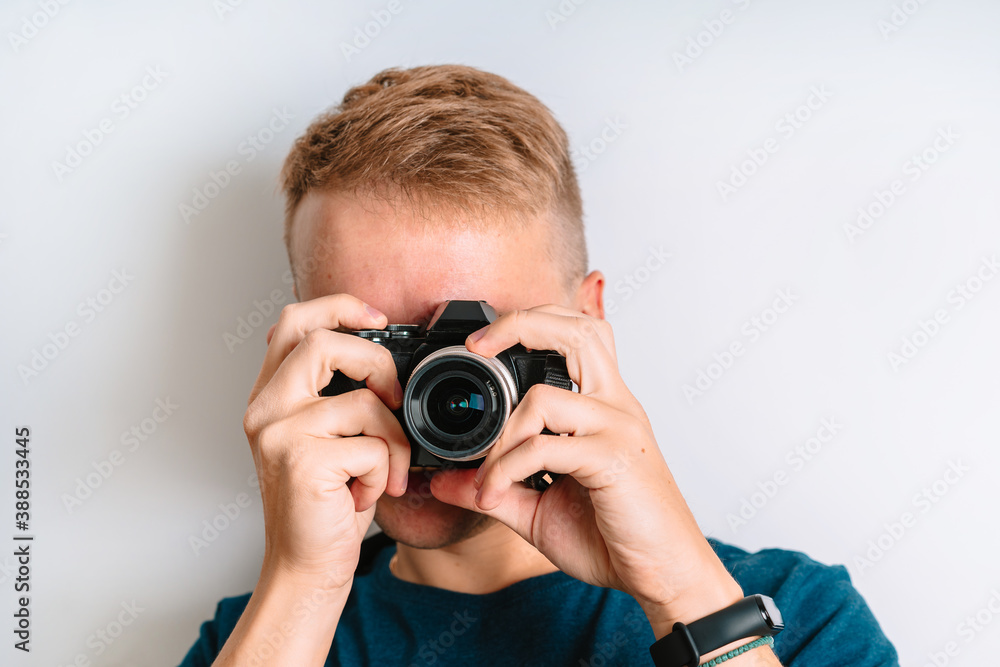Young man takes photos and looks through the viewfinder, isolated on a white background Young man takes photos and looks through the viewfinder, isolated on a white background