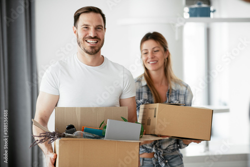 Husband and wife are moving into the apartment. Happy couple is unpacking their belongings © JustLife