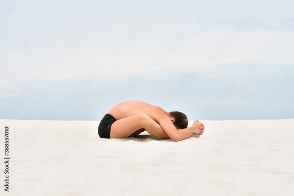Young man in relaxing yoga pose on the beach Young man in relaxing yoga pose on the beach