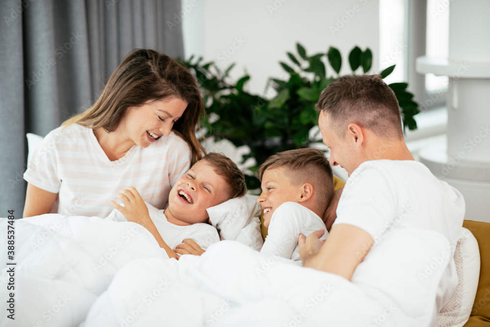 Young family enjoying in bed. Happy parents with sons relaxing in bed. Young family enjoying in bed. Happy parents with sons relaxing in bed.
