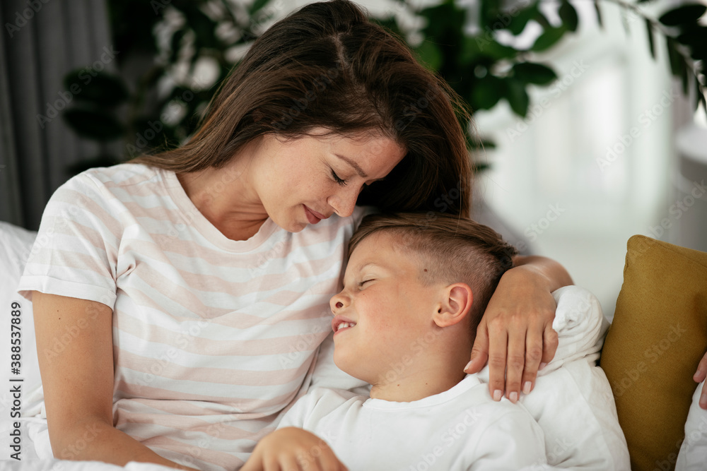 Mother and son enjoying in bed. Happy woman with son relaxing in bed.. Mother and son enjoying in bed. Happy woman with son relaxing in bed..