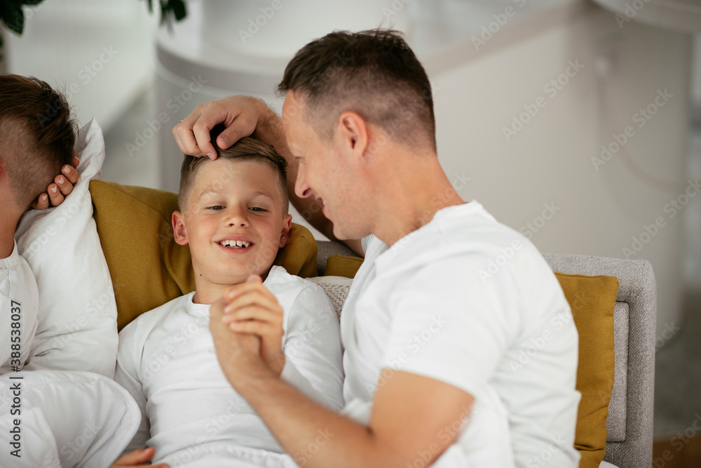 Father and son enjoying in bed. Happy man with son relaxing in bed.. Father and son enjoying in bed. Happy man with son relaxing in bed..