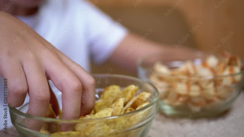 Kid Hand Takes Chips, Crackers from a Plate. Dining with Harmful Snack Foods Kid Hand Takes Chips, Crackers from a Plate. Dining with Harmful Snack Foods