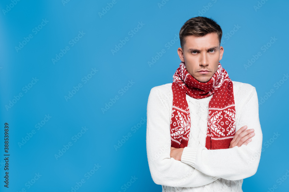 Dissatisfied man with crossed arms looking at camera isolated on blue Dissatisfied man with crossed arms looking at camera isolated on blue
