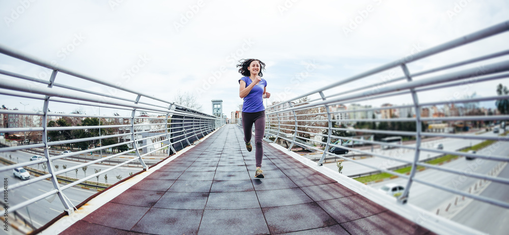 A woman runs across the bridge over the road.