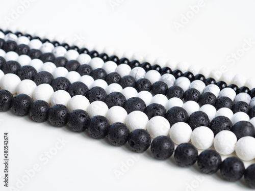 Beads from black lava stone and white coral on a white background