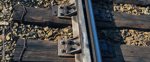 Single rail as part of a railway. Wooden sleepers and gravel are also visible.
