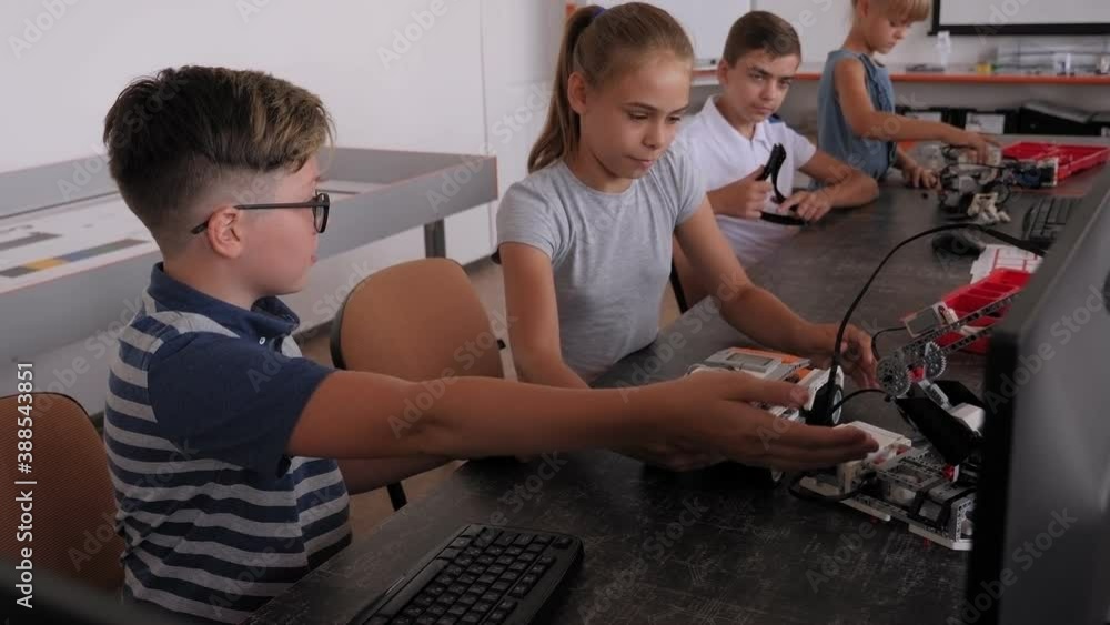 Group of kids building robot constructor from the plastics details programmed on the computer, at robotics school lesson. Group of kids building robot constructor from the plastics details programmed on the computer, at robotics school lesson.
