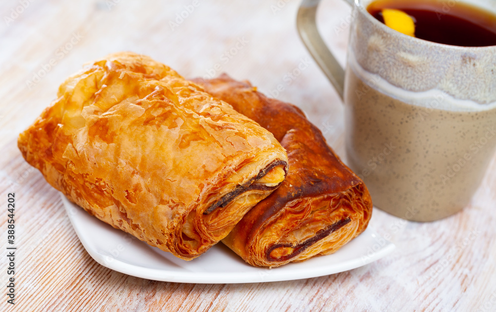 Crisp napolitana from puff pastry with meat and cheese filling served with cup of tea. Traditional Spanish pastries..