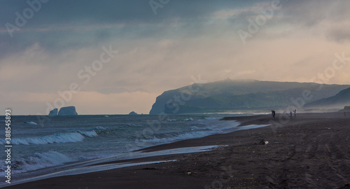 Panoramic view of the sea beach with black volcanic sand and people