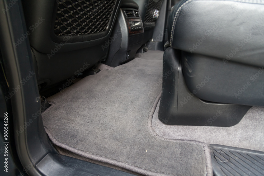 Clean carpet on the floor of passenger seats in a car made of gray fabric after washing and dry cleaning, requirements for the interior in a taxi.