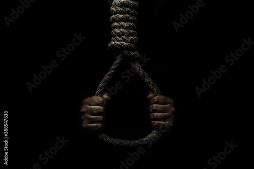 Hand holds a noose on a black background. Social problem. The end of the path