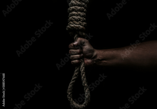 Hand holds a noose on a black background. Social problem. The end of the path photo