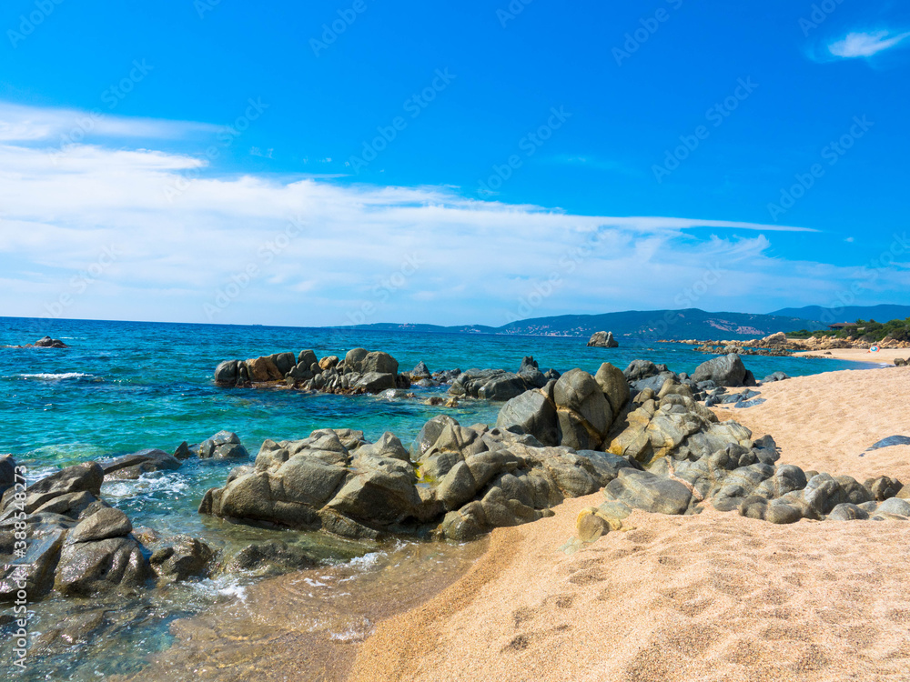 Sandstrand mit Steine in der Balagne-Region von Korsika mit türkisfarbenem Mittelmeer und klarem blauem Himmel, Korsika Frankreich