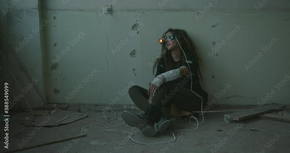 Trendy young woman in funky glasses with colorful rim lights and spot sitting on the cement floor of an old deserted building rocking herself and shaking her head. Girl wearing funky 3d glasses Trendy young woman in funky glasses with colorful rim lights and spot sitting on the cement floor of an old deserted building rocking herself and shaking her head. Girl wearing funky 3d glasses