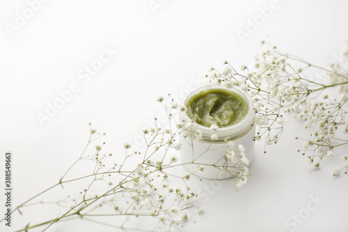 Opened plastic container with cream and flowers on a white background. face cream. herbal cream. cosmetic products. selective focus.