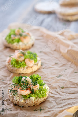 Healthy food: toast with cottage cheese, lettuce, shrimp and dill on crumpled baking paper. Shot in a high key. Vertical image.
