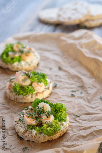 Healthy food: toast with cottage cheese, lettuce, shrimp and dill on crumpled baking paper. Shot in a high key. Vertical image.