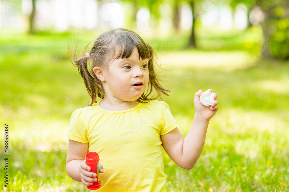 Happy girl with syndrome down blows bubbles in a summer park Happy girl with syndrome down blows bubbles in a summer park