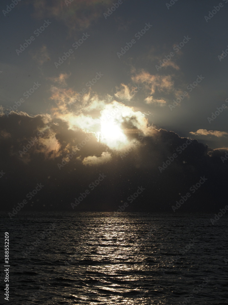 Dramatic winter sky with clouds during sunset with sunlight over ocean
