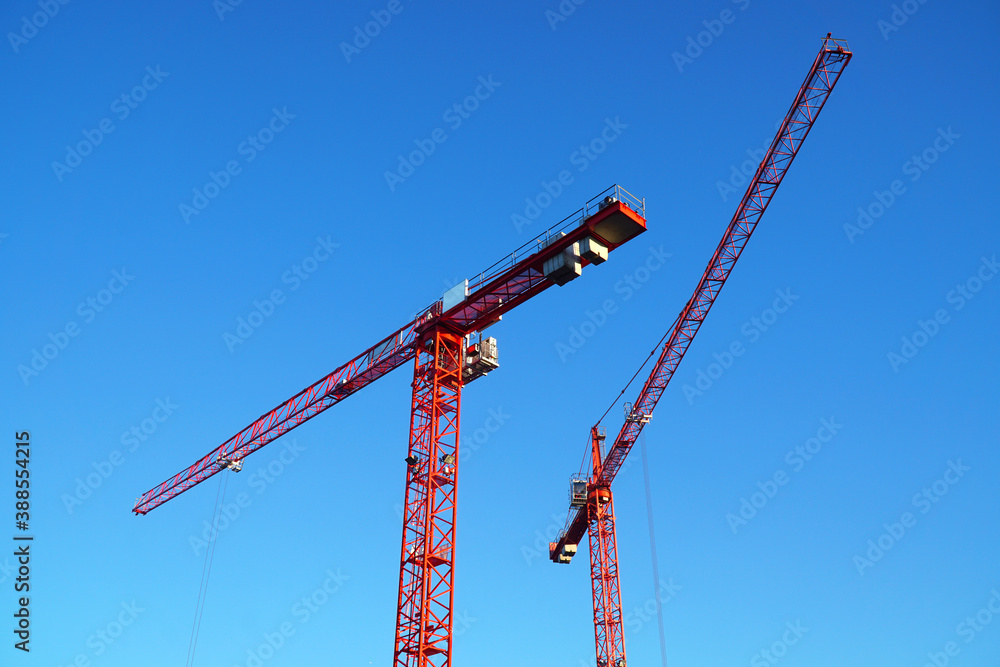 Zwei Kräne auf Baustelle vor blauem Himmel Zwei Kräne auf Baustelle vor blauem Himmel