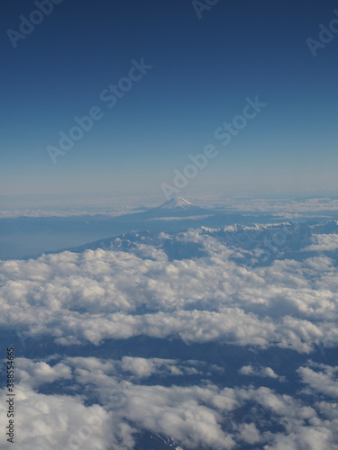 Bird's eye view of snowy Mount Fuji with white clouds over blue sky in Japan in winter