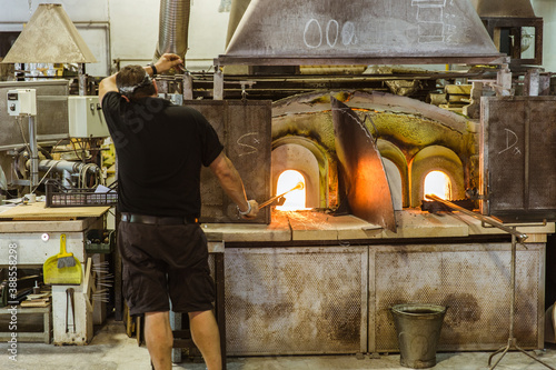 Man blowing glass to make dolphin figurine in Murano, Italy