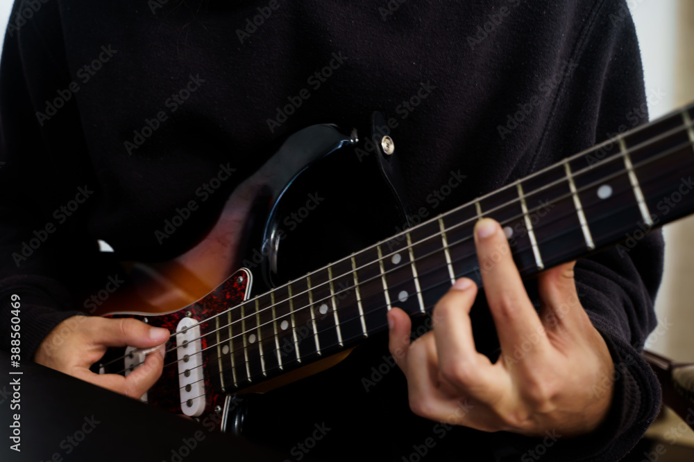 Boy playing a beautiful electric guitar of various colours with his hands