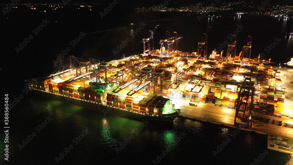Fototapeta premium Aerial drone night shot of illuminated container terminal facilities in popular Mediterranean logistics port