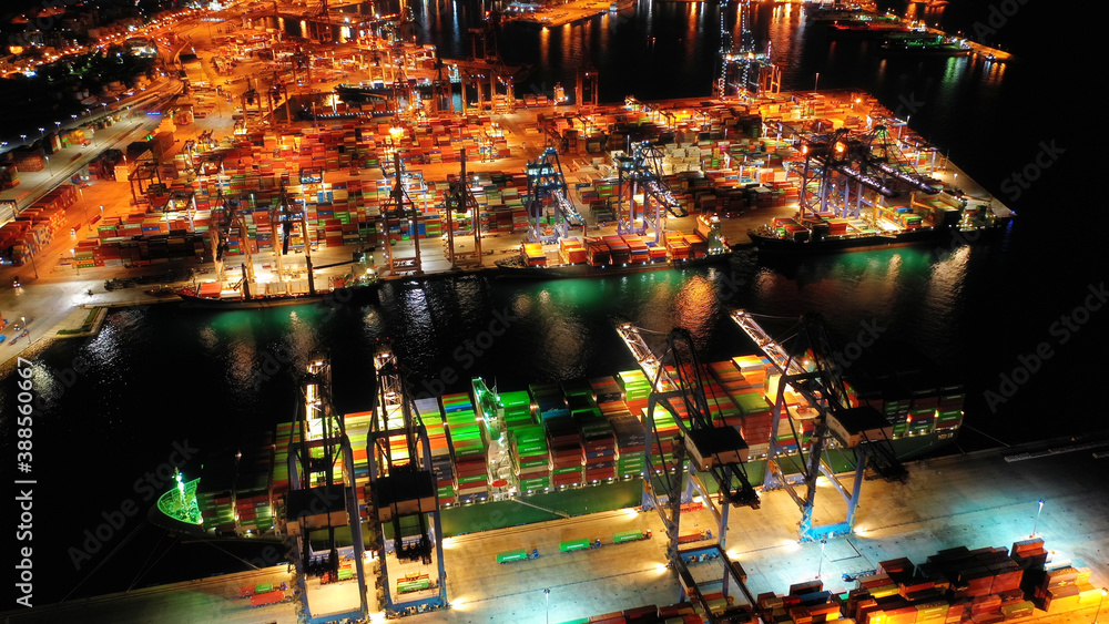Aerial drone night shot of illuminated loading/unloading container terminal in commercial port of Perama, Piraeus, Attica, Greece