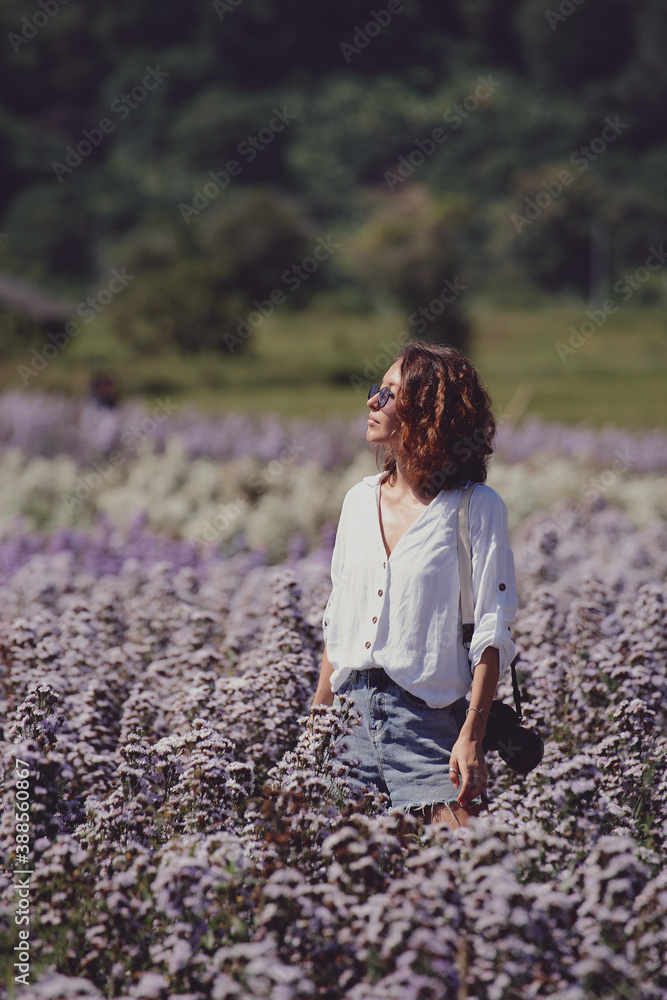 young woman professional photographer on a flower field in summer