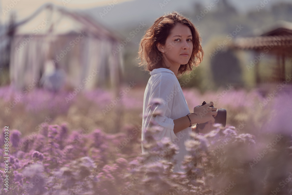 young cute woman professional photographer on a flower field in summer
