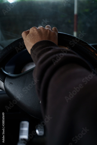 A man sitting in the seat of a car holding the steering wheel with his hand
