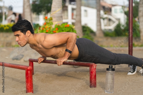 Sportsman without a shirt doing exercises on the beach
