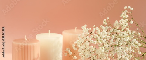 pink candles with white gypsophila flowers on pink  background with copy spac...