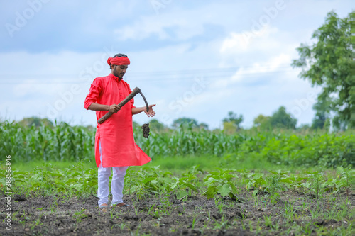 Young indian farmer hard working with farm equipment in his field photo