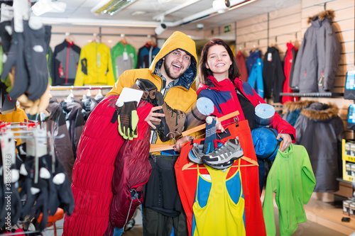 Smiling family demonstrating new tourist assortiment in sports clothes store
