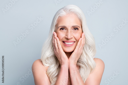 Close-up portrait of her she nice attractive cheerful grey-haired elderly lady touching silky skin cleansing isolated on gray pastel color background photo