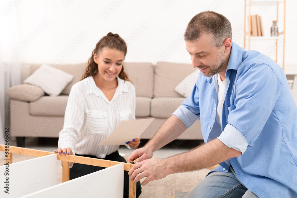 Obraz premium Happy Couple Installing Self-Assembly Furniture Kit Together Furnishing Home