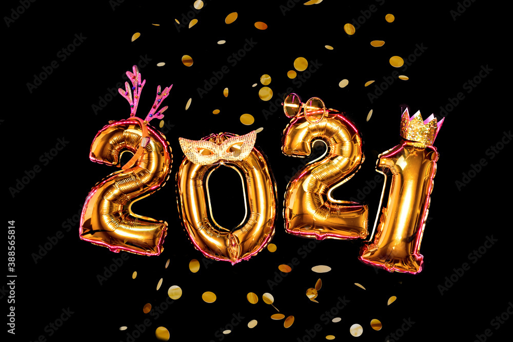 Gold glittering numbers 2021 on black background in carnival accessories, new year party concept. Confetti is flying. Gold glittering numbers 2021 on black background in carnival accessories, new year party concept. Confetti is flying.