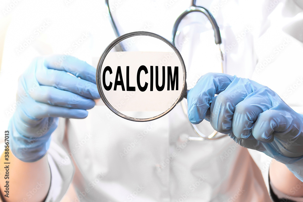 The doctor's blue - gloved hands show the word CALCIUM - . a gloved hand on a white background. Medical concept. the medicine The doctor's blue - gloved hands show the word CALCIUM - . a gloved hand on a white background. Medical concept. the medicine