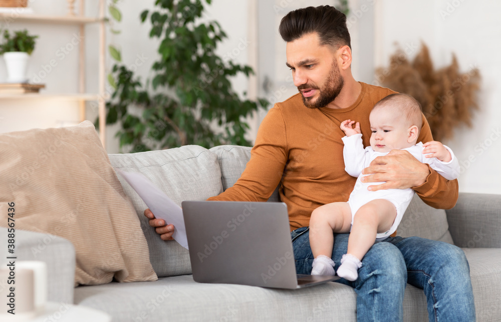 Father With Baby Working On Laptop Reading Bills At Home Father With Baby Working On Laptop Reading Bills At Home