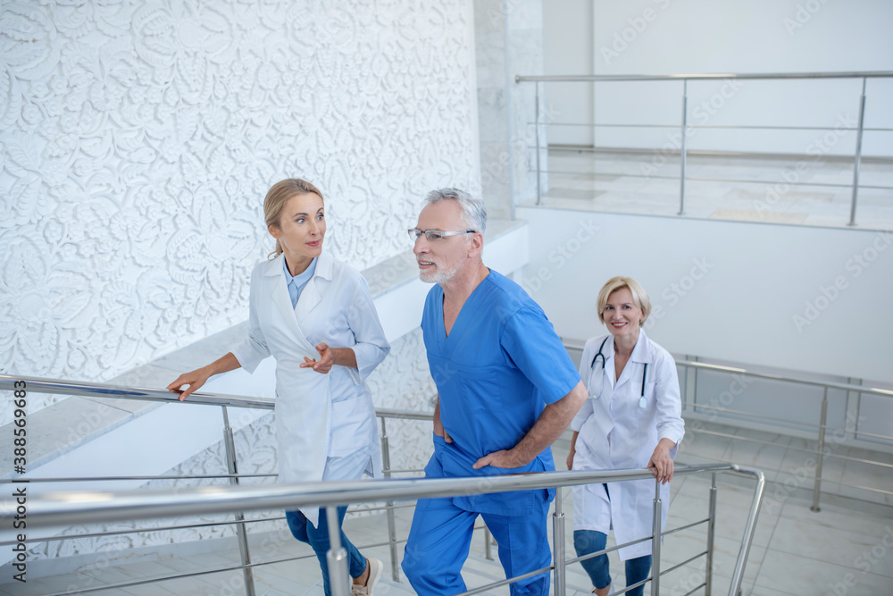 Group of professional medical workers going upstairs, having friendly conversation Group of professional medical workers going upstairs, having friendly conversation
