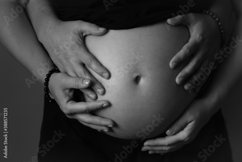 Cropped photo of beautiful pregnant woman and her husband hugging belly. pregnant woman poster.