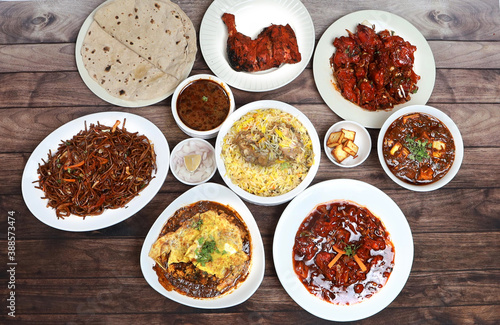 Assorted indian food on wooden background. Chicken biryani, tandoori chicken, schezwan noodles, phulka, paneer tikka masala.. Dishes and appetizers of indian cuisine