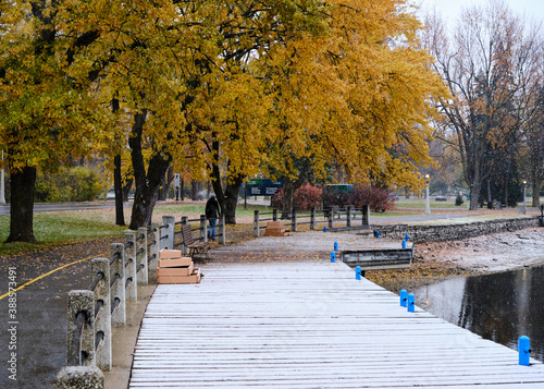  On first day of snow, snow sticking on boardwalk by the Rideau Canal, with trees still showing autumn colours photo