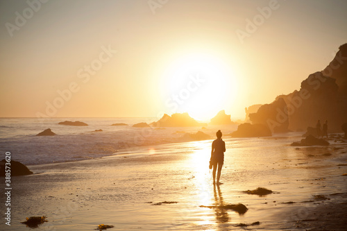Woman from behind on the beach at sunset. © luke