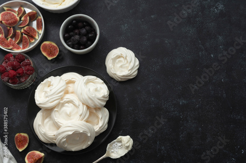 Cooking dessert. Abstract food background. Top view of mini Pavlova meringue cakes decorated with berries and figs.