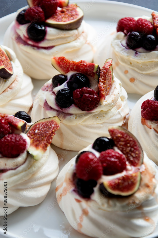 Mini Pavlova meringue cakes decorated with berries and figs. Mini Pavlova meringue cakes decorated with berries and figs.
