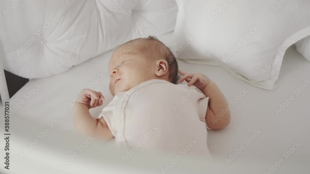 Newborn sleeps in a cot in a bright room. Little girl resting after feeding Newborn sleeps in a cot in a bright room. Little girl resting after feeding
